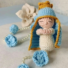 Explore a delicadeza do mini terço amigurumi em azul e rosa, destacando a mini Nossa Senhora, perfeito para momentos de fé e decoração inspiradora.