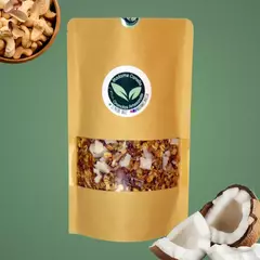 Pacote de granola Madame Canella de coco e castanhas, com pedaços de coco na embalagem e castanhas ao fundo.