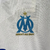 Camisa branca do Olympique de Marseille para torcedores masculinos, com detalhes em azul e logo da Puma.