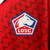 Camisa vermelha do LOSC Lille para torcedores masculinos, modelo 2024/25, com detalhes em azul e logo da New Balance.