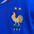 Uniforme infantil da seleção francesa, composto por camiseta azul e shorts brancos, com detalhes em vermelho e o logo da Nike.