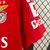 Camisa vermelha do Benfica I 2024/25, modelo masculino da Adidas, com detalhes em branco e logo do patrocinador Emirates.