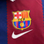 Agasalho corta vento da Nike, dupla face, com design do Barcelona em vermelho, azul e branco, apresentando detalhes como logotipo do clube e estampas relacionadas ao futebol.