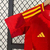 Uniforme infantil da seleção da Espanha, composto por camiseta vermelha com detalhes amarelos e calção azul, da marca Adidas.