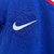 Uniforme infantil da seleção francesa, composto por camiseta azul e shorts brancos, com detalhes em vermelho e o logo da Nike.