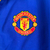 Agasalho corta vento da Manchester United, modelo 2023/24, nas cores verde e azul, com detalhes em amarelo e logo da Adidas.