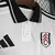 Camisa branca do Fulham I 2024/25 para torcedores masculinos, com detalhes em vermelho e preto, confeccionada pela Adidas.