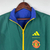 Agasalho corta vento da Manchester United, modelo 2023/24, nas cores verde e azul, com detalhes em amarelo e logo da Adidas.