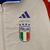 Agasalho Corta Vento Itália Dupla Face 2023/24 da Adidas, na cor azul e branca, exibindo o logo da seleção italiana e detalhes em verde nas mangas.

