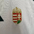 Camisa branca masculina da seleção da Hungria, modelo 2024/25, com detalhes em verde e vermelho, e logos da Adidas e da federação húngara.