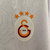 Camisa branca do Galatasaray II 2024/25, masculina, da marca Puma, com detalhes em vermelho e laranja, e logotipo da equipe e patrocinador.