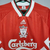 Camisa retrô do Liverpool, modelo home de 1993, nas cores vermelha e branca, com detalhes em verde e logotipo da Adidas.