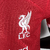 Camisa do Liverpool I 2023/2024, modelo jogador masculina, cor vermelha, da Nike, com detalhes do logotipo e patrocinador.