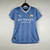 Camisa feminina do Manchester City 2023/2024, na cor azul, com logo da Puma e patrocínio da Etihad Airways.