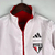 Agasalho corta vento vermelho e branco da Adidas, modelo São Paulo, com logo do clube e listras nas mangas.