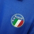 Camisa retrô da seleção italiana de futebol, modelo azul, com logo e detalhes coloridos na gola.

