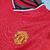 Camisa retrô do Manchester United da temporada 2000/2001, na cor vermelha, com detalhes em preto e logo da Umbro.

