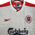 Camisa retrô do Liverpool da temporada 1998/1999, branca com detalhes em vermelho, logotipo da Reebok e patrocínio da Carlsberg.

