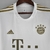 Camisa branca do Bayern de Munique, modelo Away 22/23, com detalhes em dourado e logotipo da Adidas.

