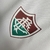 Camisa de treino branca do Fluminense, com detalhes em verde e vermelho, e logo do clube.