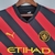 Camisa do Manchester City Away 22/23 na cor preta e vermelha, com detalhes em amarelo e logo da Puma.

