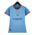 Camisa feminina do Manchester City na cor azul, modelo 22/23, com detalhes em vermelho e logo da Puma.