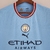 Camisa azul do Manchester City, modelo 22/23, com detalhes em vermelho e logo da Puma.

