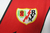 Camisa branca do Rayo Vallecano I 22/23, com detalhes em vermelho e logo da Umbro.

