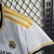 Camisa feminina do Real Madrid I 23/24 da Adidas, na cor branca, com detalhes em amarelo e preto.

