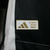 Camisa preta e branca da Juventus, modelo 24/25, com logo da Adidas e detalhes em listras verticais.

