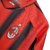 Camisa retrô do AC Milan da temporada 2004/2005 nas cores vermelha e preta, com detalhes em preto e o logo da Adidas.

