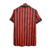 Camisa retrô do AC Milan da temporada 1999/2000, nas cores vermelha e preta, com listras verticais e detalhes da marca Adidas.

