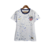 Camisa feminina branca da seleção dos Estados Unidos, com estampa salpicada em azul, logo da Nike e escudo da seleção.