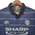 Camisa retrô do Manchester United da temporada 1999/2000, na cor azul, com detalhes em listras brancas e logo da Umbro.

