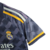 Camisa feminina do Real Madrid, modelo Away 23/24, na cor cinza com detalhes em amarelo.

