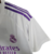 Camisa branca do goleiro do Real Madrid 23/24 com detalhes em roxo e logo da Adidas.

