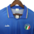 Camisa retrô da seleção italiana de futebol, modelo azul, com logo e detalhes coloridos na gola.

