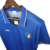 Camisa retrô da seleção italiana de futebol, modelo azul, com logo e detalhes coloridos na gola.

