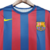 Camisa retrô do FC Barcelona de 2006, nas cores azul e vermelha, com listras verticais e logo da Nike.

