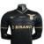 Camisa preta da Lazio Edição Especial 23/24, com detalhes em dourado, logotipo da Mizuno e patrocínio da Binance.

