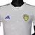 Camisa branca do Leeds United com detalhes em azul e amarelo, modelo 23/24 da Adidas para jogadores masculinos.

