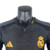 Camisa do Real Madrid III 23/24, modelo masculino da Adidas, na cor preta com detalhes em amarelo, exibindo o logo do clube e o patrocinador.

