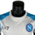 Camisa Napoli Edição Especial 23/24 branca com detalhes em azul, estampada com logotipo EA7 e imagens de jogadores.

