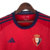 Camisa vermelha do Osasuna I 23/24, com detalhes em azul e branco e logo da Adidas.

