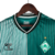 Camisa de futebol masculina do Werder Bremen I 23/24, predominantemente branca e verde com detalhes em preto e listras verticais.

