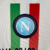 Camisa branca do Napoli, edição especial 23/24, com detalhes em vermelho e verde, estampada com 'Campioni d'Italia 22/23' e o logo da EA7.

