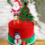 Topo de bolo de Natal com Papai Noel em uma escada, árvore de Natal e boneco de neve decorativo.