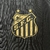 Logotipo do Santos Futebol Clube em uma camisa retrô, com detalhes em dourado e preto.