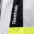 Detalhe da camiseta branca do Botafogo, com a marca Reebok em destaque na lateral.