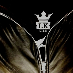 Close-up de uma camiseta preta da marca LK-LIKE com zíper e um logo branco que diz "LK" e uma coroa acima.